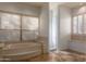 Bathroom featuring a large tub, tiled floors, and two windows with plantation shutters at 3631 S Greythorne S Way, Chandler, AZ 85248