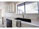 Close up view of a stainless steel sink, black faucet, white cabinets, quartz countertops and a modern black dishwasher at 38234 N 15Th Ave, Phoenix, AZ 85086