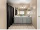 Bathroom featuring dual sink vanity, shower with black curtain, and neutral tile floor at 8812 N 67Th Dr, Peoria, AZ 85345