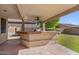 This covered outdoor kitchen offers a built-in BBQ, bar seating, and patio perfect for entertaining at 9237 W Alex Ave, Peoria, AZ 85382