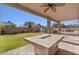 Enjoy the cozy covered patio with a stone fire table and view of the manicured backyard at 9237 W Alex Ave, Peoria, AZ 85382