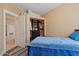 Cozy bedroom features a blue bedspread, closet organizers, and a doorway to an adjacent room at 9718 E Boston St, Mesa, AZ 85207