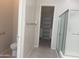 Bright bathroom featuring tile flooring, toilet, glass enclosed shower and walk in closet at 9734 S 182Nd Dr, Goodyear, AZ 85338