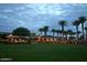 Elegant clubhouse featuring well-manicured lawns, palm trees, and inviting exterior lighting at 9734 S 182Nd Dr, Goodyear, AZ 85338