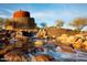 Scenic entrance to a community, showcasing a waterfall, stone architecture, and natural desert landscape at 9734 S 182Nd Dr, Goodyear, AZ 85338