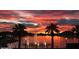 Sunset view of a community pond with fountains, framed by palm trees and colorful sky at 9734 S 182Nd Dr, Goodyear, AZ 85338