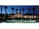 Inviting community pool and clubhouse, framed by palm trees, and lit up at twilight at 9734 S 182Nd Dr, Goodyear, AZ 85338