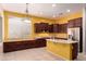 This kitchen is equipped with dark wood cabinets, a stainless steel refrigerator, and a functional island workspace at 9734 S 182Nd Dr, Goodyear, AZ 85338