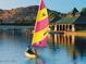 Person sailing in a small sailboat on a tranquil lake with a clubhouse in the background at 9734 S 182Nd Dr, Goodyear, AZ 85338