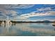 Scenic view of the lake featuring a water fountain, lush landscaping, and distant mountains on the horizon at 9734 S 182Nd Dr, Goodyear, AZ 85338