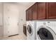 Laundry room with white washer and dryer, dark cabinets, and tiled flooring at 9734 S 182Nd Dr, Goodyear, AZ 85338
