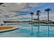 Inviting pool area with views of the lake, palm trees and shaded lounge seating, creating a resort-like atmosphere at 9734 S 182Nd Dr, Goodyear, AZ 85338