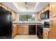 Functional kitchen with black appliances, wood cabinetry, and a view of the outdoors at 9990 N Scottsdale Rd # 1006, Paradise Valley, AZ 85253