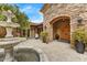 Stone archway frames double doors, leading to outdoor courtyard with fountain at 10798 E Hedgehog Pl, Scottsdale, AZ 85262