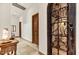 Elegant hallway with travertine floors leads to a stunning wrought iron wine cellar door at 10798 E Hedgehog Pl, Scottsdale, AZ 85262