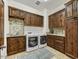 Well-equipped laundry room with knotty alder cabinetry and stacked stone accent wall at 10798 E Hedgehog Pl, Scottsdale, AZ 85262