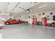 Spacious garage featuring an orange sports car, epoxy floors, storage cabinets, and car-themed wall art at 15642 E Palatial Dr, Fountain Hills, AZ 85268