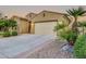 Home exterior with a spacious driveway and a two-car garage, surrounded by desert landscaping and palm trees at 15829 W Bonitos Dr, Goodyear, AZ 85395