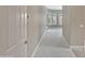 Hallway with neutral carpeting leading to a bright, window-filled room at 15829 W Bonitos Dr, Goodyear, AZ 85395