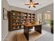 Stylish home office with a large wooden desk, ample shelving, and natural light at 15829 W Bonitos Dr, Goodyear, AZ 85395