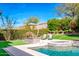 This backyard features a sparkling pool and spa with an outdoor stone fireplace and two lounge chairs at 1918 W Medinah Ct, Anthem, AZ 85086