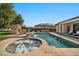 Inviting backyard features a pool, spa, built-in stone fireplace, and lush landscaping, perfect for outdoor entertaining at 1918 W Medinah Ct, Anthem, AZ 85086