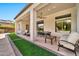 Covered patio with an outdoor dining area and seating, ceiling fan, artificial grass, and stone accents at 1918 W Medinah Ct, Anthem, AZ 85086