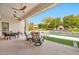 Covered patio showing outdoor seating, ceiling fans, and a view of the pool, stone fireplace, and landscaped yard at 1918 W Medinah Ct, Anthem, AZ 85086