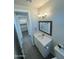 Neat bathroom showcasing a framed mirror, vanity with sink, stylish lighting, and gray wood-look flooring at 27411 N 256Th Dr, Wittmann, AZ 85361