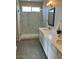 Spacious bathroom boasting double sinks, framed mirrors, modern lighting, and gray wood-look flooring at 27411 N 256Th Dr, Wittmann, AZ 85361