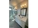 Spacious bathroom boasting double sinks, framed mirrors, modern lighting, and gray wood-look flooring at 27411 N 256Th Dr, Wittmann, AZ 85361