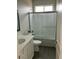 Well-lit bathroom featuring a glass shower door, with a shower-over-tub combo, and sleek gray wood-look flooring at 27411 N 256Th Dr, Wittmann, AZ 85361