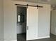 Charming bathroom is visible through this barn door; it features a vanity and elegant lighting at 27411 N 256Th Dr, Wittmann, AZ 85361