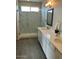 Spacious bathroom boasting double sinks, framed mirrors, modern lighting, and gray wood-look flooring at 27411 N 256Th Dr, Wittmann, AZ 85361