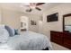 Cozy bedroom with a patterned comforter, ceiling fan, and en suite bathroom at 42578 W Rosalia Dr, Maricopa, AZ 85138