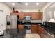 Well-lit kitchen featuring wood cabinets, stainless steel appliances, and dark countertops at 42578 W Rosalia Dr, Maricopa, AZ 85138