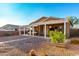 Lush backyard with a covered patio, desert landscaping, rock stream, and charming trees, creating a serene outdoor space at 4267 S Strong Box Rd, Gold Canyon, AZ 85118