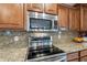 Close-up of modern kitchen features including granite countertops, stainless steel appliances, and rich wood cabinetry at 518 E Laddoos Ave, Queen Creek, AZ 85140