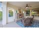 Cozy covered patio with a stone fireplace, comfortable seating, and a ceiling fan, perfect for outdoor relaxation at 518 E Laddoos Ave, Queen Creek, AZ 85140