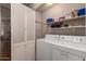 Functional laundry room equipped with storage shelves, a folding door, and a washer and dryer for convenience at 5802 E Fountain St, Mesa, AZ 85205