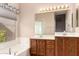 Bright bathroom featuring a soaking tub, double sinks, and a large vanity mirror at 653 S Catalina St, Gilbert, AZ 85233