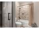 This bathroom features a shower-tub combo and unique textured walls for a modern feel at 6881 W Greenbriar Dr, Glendale, AZ 85308