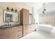 Bathroom featuring double sinks, wooden cabinetry, modern fixtures, and a freestanding tub by the window at 9246 N 108Th St, Scottsdale, AZ 85259