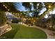 Expansive backyard featuring manicured lawn, ambient string lights, and a cozy sunken seating area at 12593 E Desert Cove Ave, Scottsdale, AZ 85259