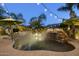 Beautiful backyard pool with rock waterfall feature, lush landscaping and ambient lighting at 12593 E Desert Cove Ave, Scottsdale, AZ 85259