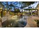 Backyard with a captivating pool featuring a waterfall, ambient lighting, and verdant surroundings at 12593 E Desert Cove Ave, Scottsdale, AZ 85259