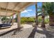 Expansive covered patio with patio furniture, surrounded by landscaped yard and mature palm trees at 15039 W Rounders Dr, Surprise, AZ 85374