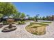 Well-maintained backyard with a fountain, lush lawn, and a basketball court in the distance at 18131 W Palo Verde Ct, Litchfield Park, AZ 85340