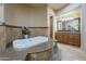 Elegant bathroom featuring a whirlpool tub with tile surround and a double sink vanity at 18131 W Palo Verde Ct, Litchfield Park, AZ 85340