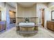 Luxurious bathroom featuring a step-up tub, travertine floors, granite counters, and custom cabinetry at 18131 W Palo Verde Ct, Litchfield Park, AZ 85340
